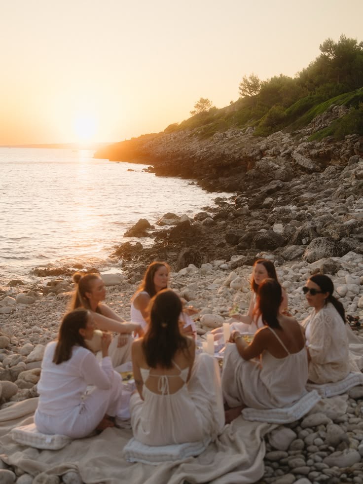 Amigas reunidas en círculo junto al mar, al atardecer